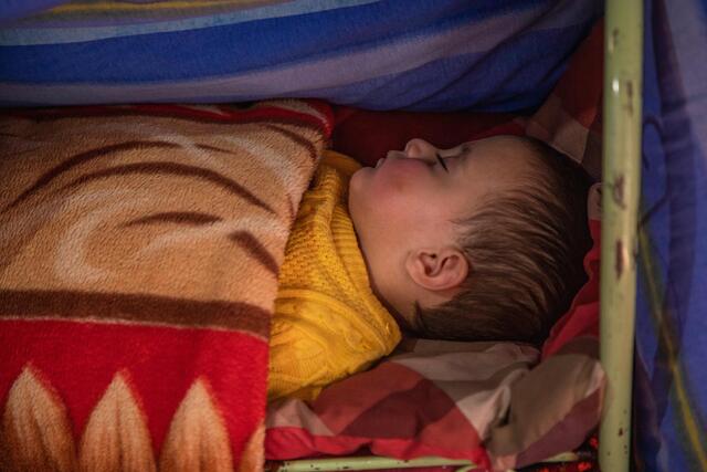A close up of Zulaykha’s one-year-old son sleeping covered with a blanket