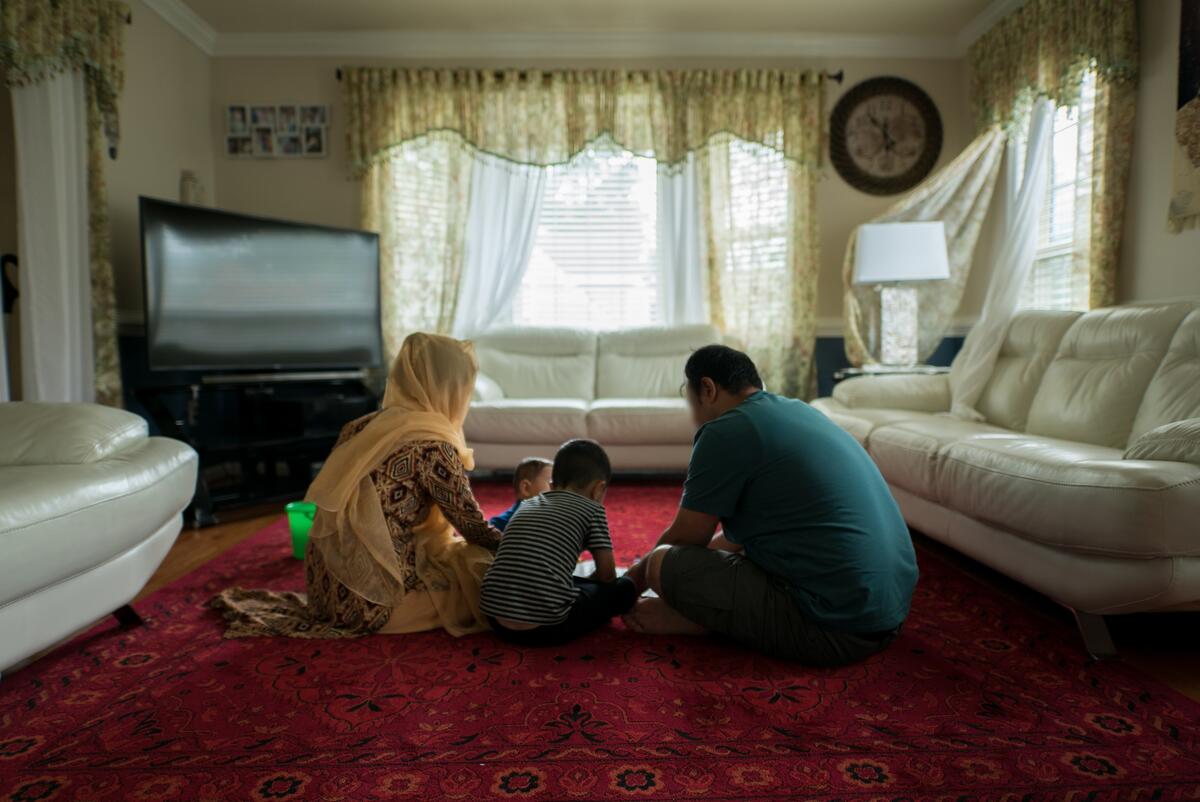 Afghan refugees Hadiya and Ali play with their two young children on the living room carpet of a friend's home in Virginia