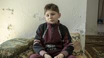 A boy sitting on a matress on the floor