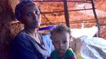 A woman and a young child in a simple tent