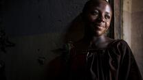 A women is smiling and leaning against a wall