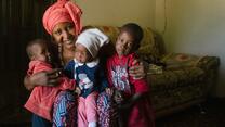 Jafiada sits with her three children on a sofa and smiles