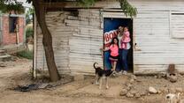 mother with two children and dog in front of her wooden cabin