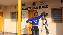 patience posing with her camera in front of an office