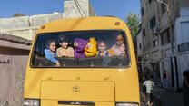Kids and sesame street puppets looking out of the back window of a bus
