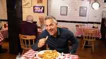 Gary Lineker sitzt an einem Tisch und isst Fish & Chips.