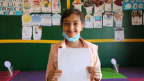 Joumana holding her schoolwork towards the camera
