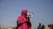 Eine somalische Frau mit einer pinken Burkha spricht durch ein Megafon zu anderen Frauen. Äthiopien geflohen. Heute setzt sich sich im Helowyn Camp für die Rechte von Frauen und Mädchen ein. 