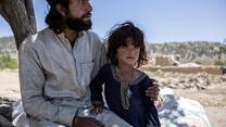 Afghanistan earthquake - An older brother holds his younger sister while looking at the damage to their house