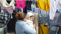 A Guatemalan mother stands holding her baby amid laundry hanging out to dry in Ciudad Juárez, Mexico.