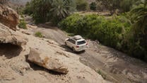white car driving along a rocky remote road