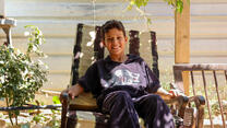 A 10-year-old Syrian boy sits in a chair outside under the shade of a grapevine arbor in a refugee camp in Jordan