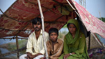 파키스탄 홍수 후 텐트 아래 앉아 있는 가족