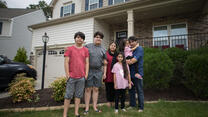 Photo of former Afghan refugee Noori standing outside his house with his family