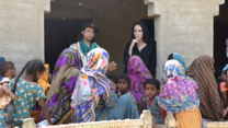 Angelina Jolie visits with women affected by flooding and Pakistan. A few girls look on at the forefront of the picture.