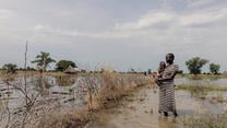 Abuk Deng holding her 4-year-old daughter Nyirou in front of their flooded home in Northern Bahr el Ghazal, South Sudan.