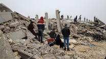 A group of survivors standing in rubble following the February 2023 earthquake in Syria.