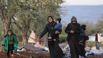 Syrians, displaced as a result of the deadly earthquake that hit Turkey and Syria on February 6, walk in an open field.