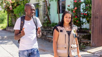 Jean Michael walks down a street next to an IRC staff member.