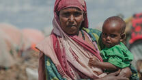 Somalia klimatkris: en mamma håller i sitt barn på ett flyktingläger. 
