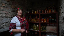 Woman standing in a storage room with preserved food in jars behind her