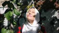 Fariba, an Afghan refugee, standing in the sunlight looking happy