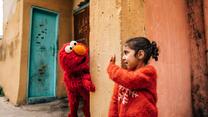 Ein kleines Mädchen winkt Elmo
