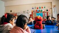 Children in a school classroom with character from Sesame Street