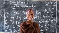 A girl stands in front of a school chalkboard.