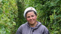 A woman poses for a portrait in a field.