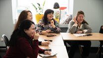 Women sit around the table talking and laughing in a Dnipro safe space funded by the EU