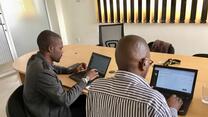 Two people working on laptops seated at a desk.