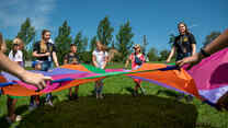 A group of people people playing with a ribbon kite.