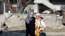 Two girls stand together and pose for a photo outside