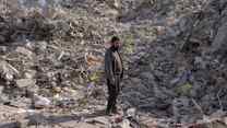 A man stands in the midst of the rubble of a building destroyed in the Syria-Turkey earthquake.