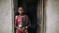A girl poses for a photo while standing in a doorway in the Democratic Republic of Congo.
