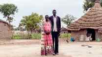 A man and woman poses for a photo outside their home in South Sudan.