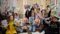 A group of Ukrainian refugee children hold up new books that they've recieved.