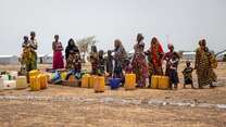 A group of women and children stand near a water collection point in Burkina Faso