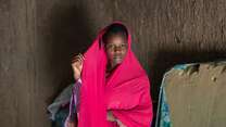 A schoolchildren in Niger, wearing a pink outfit, poses solemnly for a potrait