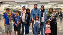 A family poses for a photo together after being reunified at an airport.