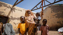 En familj i Sudan står vid sin bostad som saknar tak. 