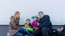 A family of four, who have recently fled war in Ukraine, pose for a picture. One of them, a young boy, holds the family's cat.