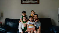 A family of five smile and pose together for a portrait.