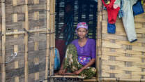A woman poses for a photo while sitting in the opening of a doorframe.