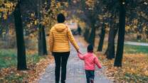Frau und Kind Hand in Hand in einer Allee