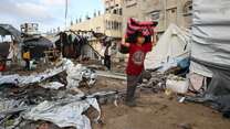 Ein Junge trägt eine Decke durch ein zerstörtes Stadtviertel in Gaza.