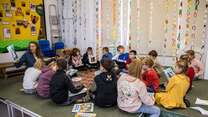 Kinder sitzen im Klassenraum und hören einer Vorlesung zu.