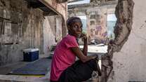 A woman poses for a picture in the remnants of a destroyed building in Haiti.