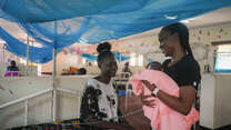 IRC Health Manager Dr. Sila holds newborn baby Blessing and talks with her mother Hiba.